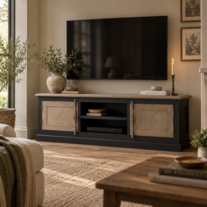 A black TV stand with rustic beige wood doors and a light stone top, styled in a cosy living room with a wall-mounted TV, candles, and plants.