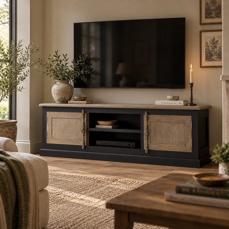 A black TV stand with rustic beige wood doors and a light stone top, styled in a cosy living room with a wall-mounted TV, candles, and plants.