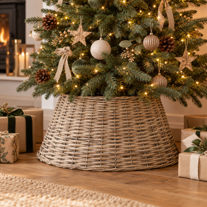 Wicker tree skirt around the base of a decorated Christmas tree, with wrapped presents on a wooden floor