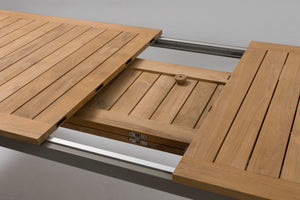 Close-up of a wooden table extension with slatted panels and metal rails, shown in a clean studio-style setting.