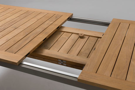 Close-up of a wooden table extension with slatted panels and metal rails, shown in a clean studio-style setting.