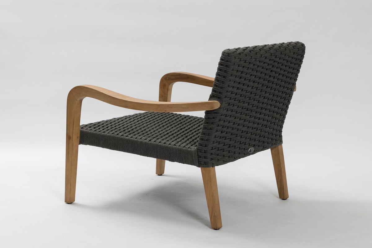 A modern outdoor lounge chair with a black woven rope seat and backrest, supported by curved light brown wooden arms and legs, shown from a three-quarters angle on a light grey studio background.