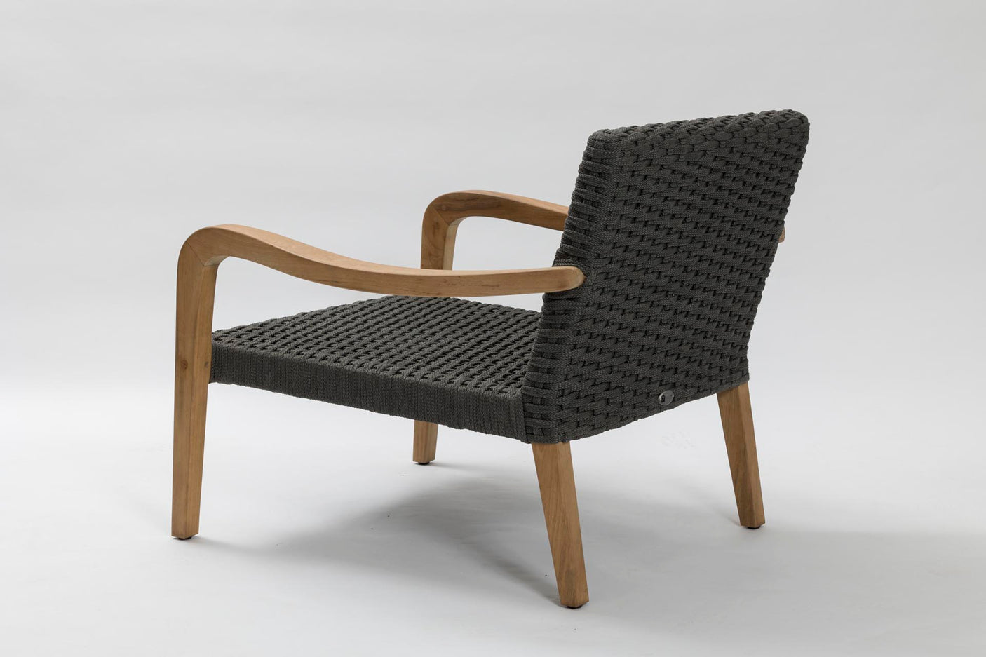 A modern outdoor lounge chair with a black woven rope seat and backrest, supported by curved light brown wooden arms and legs, shown from a three-quarters angle on a light grey studio background.