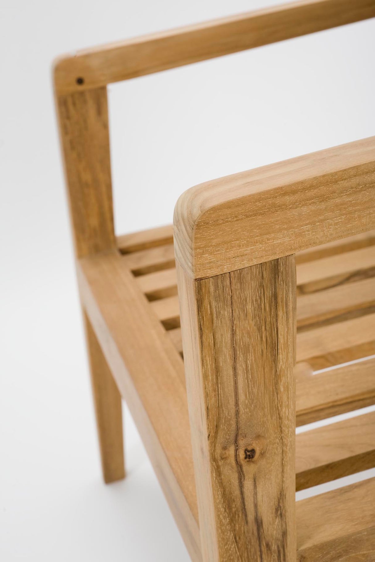 Close-up of a light natural wood outdoor chair showing the armrest, slatted seat, and clean white background.