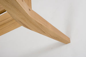 Close-up of a light natural wood chair leg against a plain white background.