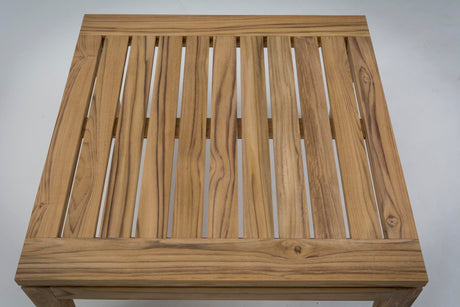 A square wooden slatted table top with a natural teak-like grain, shown from a top-down perspective against a light grey background.