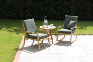 Two wooden chairs with gray cushions and a small round table on a patio area.