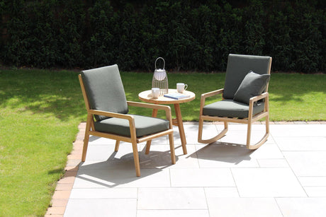 Two wooden chairs with gray cushions and a small round table on a patio area.