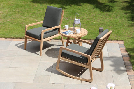 Outdoor patio set with two chairs and a small table on a paved area with grass in the background.