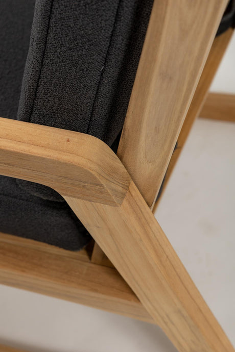 Close-up of a wooden chair with a black cushion on a light background