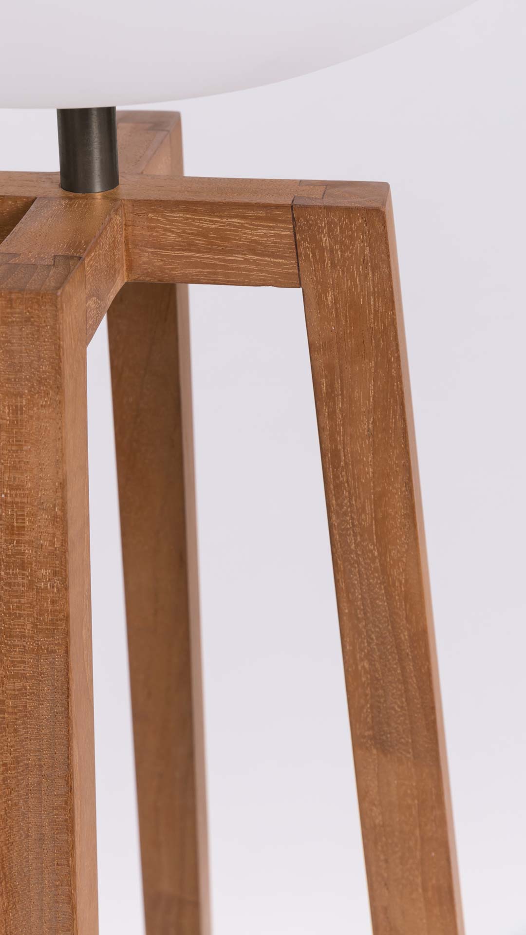 Close-up of a wooden lamp base with a white shade on a white background