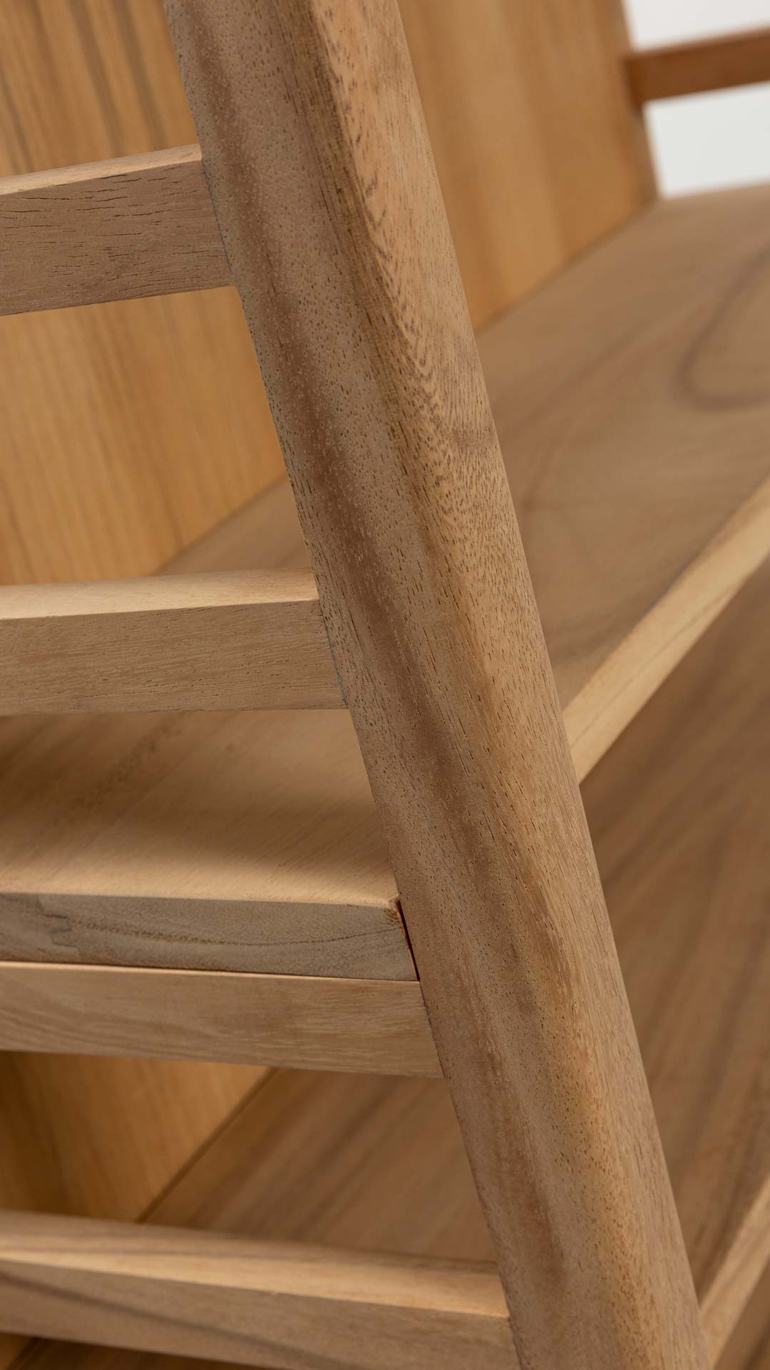 Close-up detail of a light natural wood furniture piece, showing the grain and layered slatted structure.