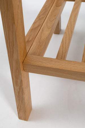 Close-up of a light oak wood furniture leg and frame corner on a white background.